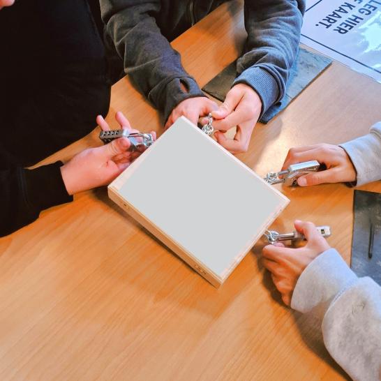 Handen die een escape-box proberen open te maken